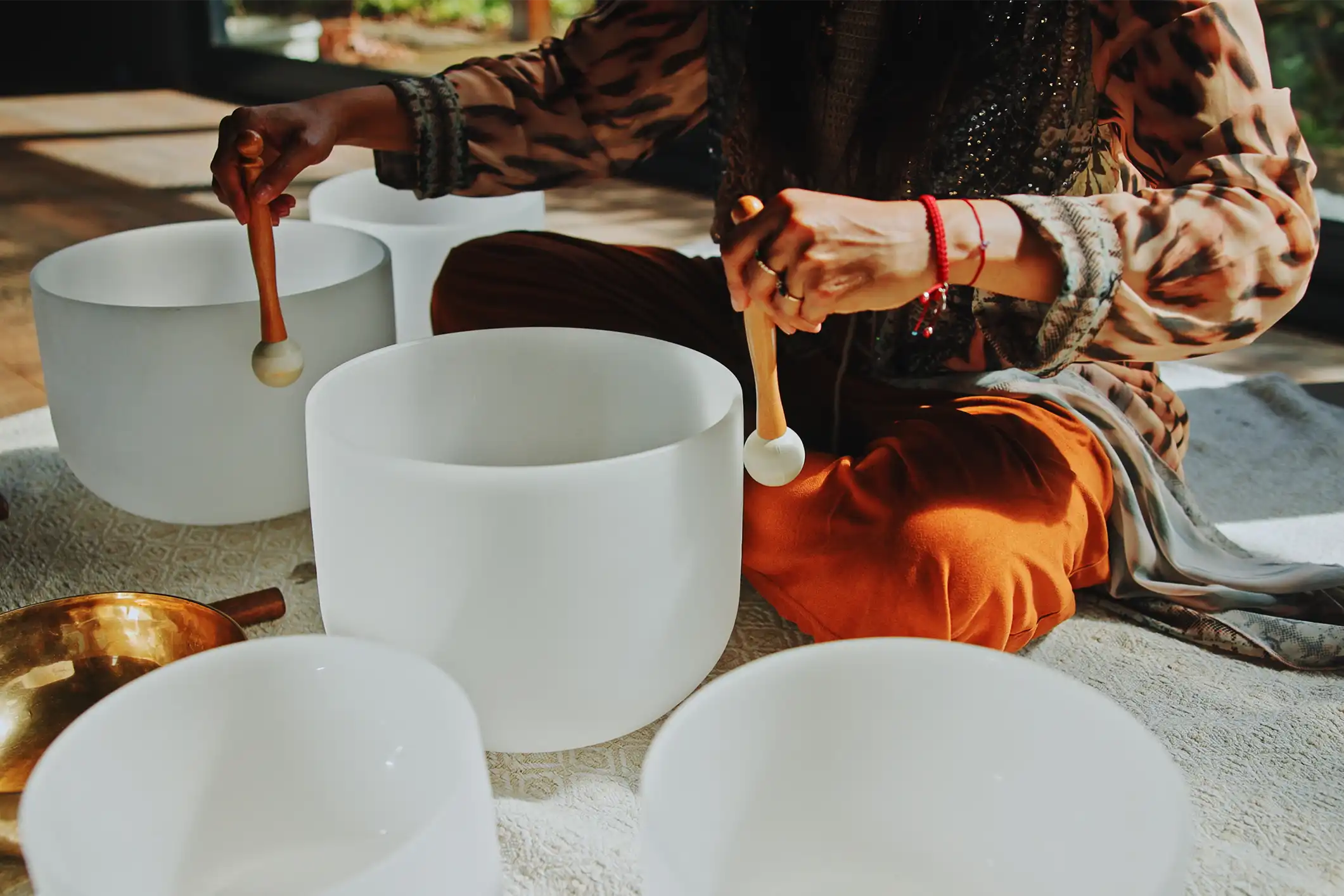 A pair of hands rotating mallets around large white bowls