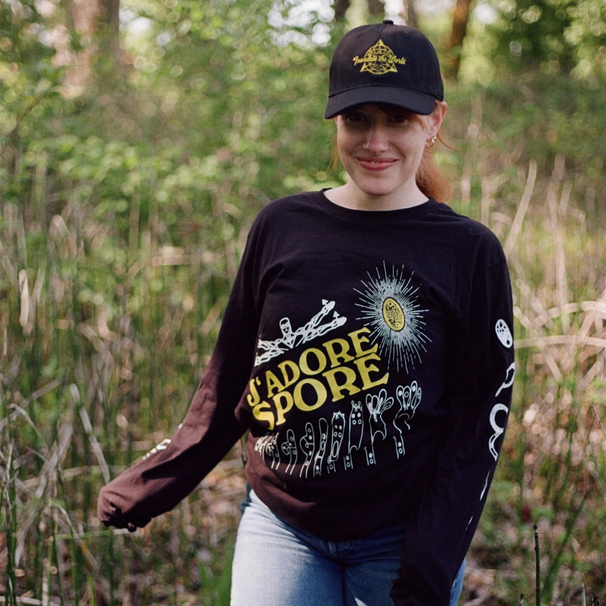A woman wearing a black baseball cap, and a black shirt displaying yellow logos.